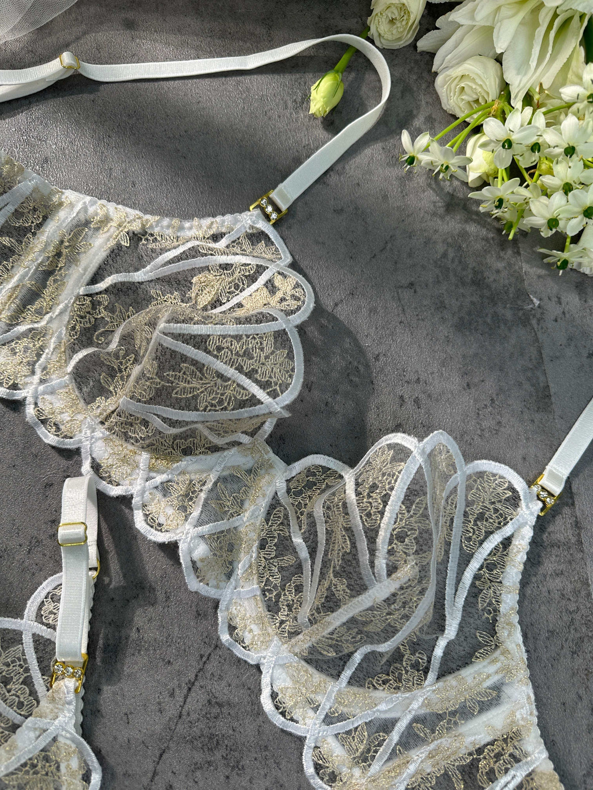 The Heavenly Glow bridal lingerie set highlighting the opulent golden embroidery against a backdrop of smooth white satin.