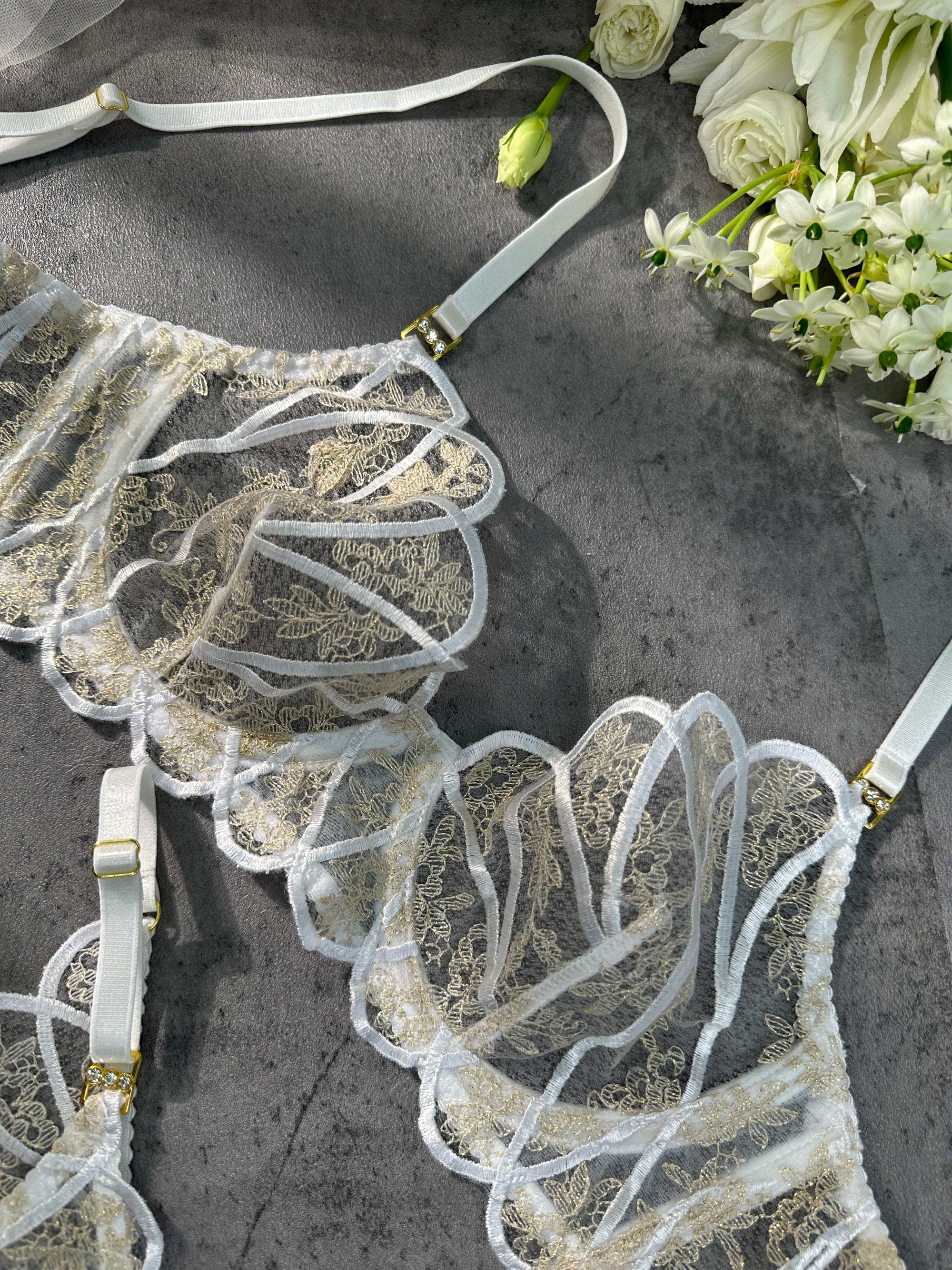 The Heavenly Glow bridal lingerie set highlighting the opulent golden embroidery against a backdrop of smooth white satin.