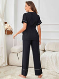 Pyjamaset met contrasterende bies, riem, top en broek in een minimalistische en bescheiden stijl.